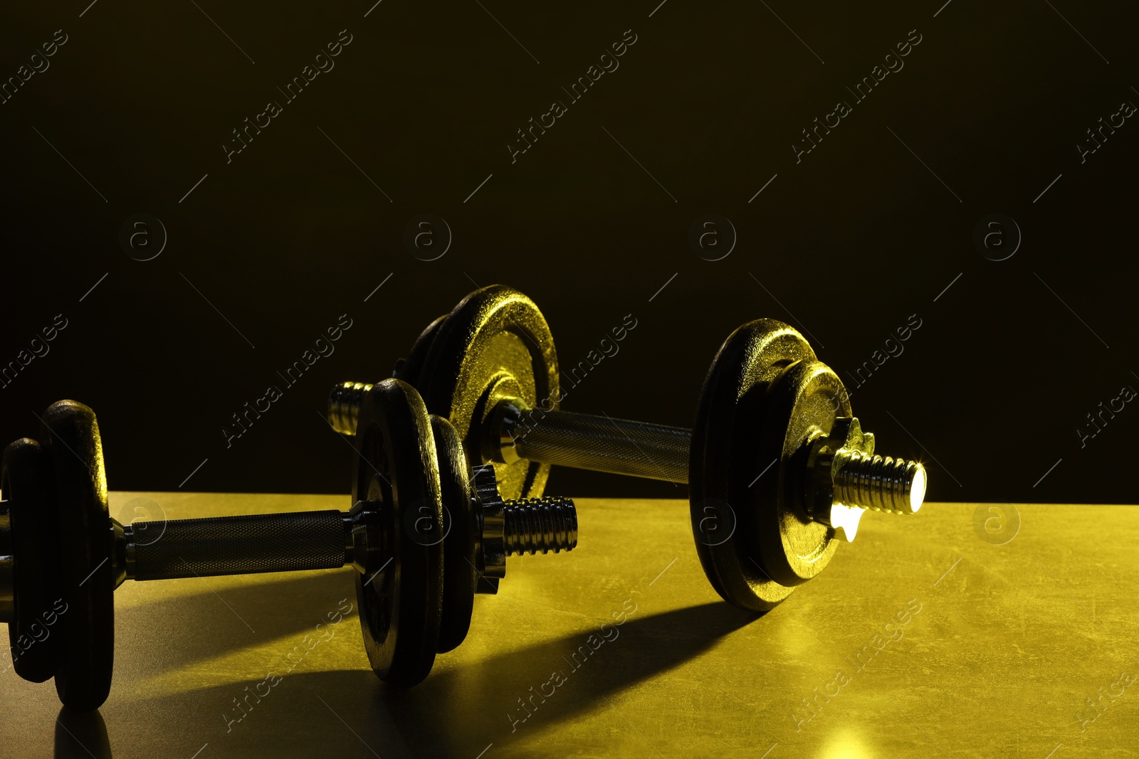 Photo of Two barbells on table in color lights, closeup