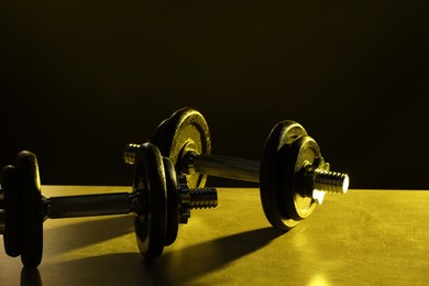 Two barbells on table in color lights, closeup