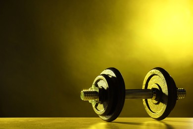 Photo of Barbell on table in color lights. Space for text