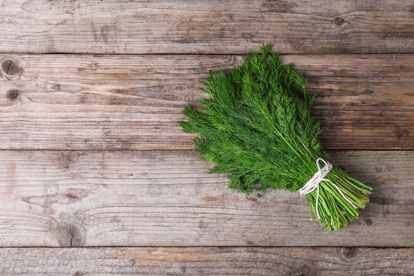 Photo of Bunch of fresh green dill on wooden table, top view. Space for text