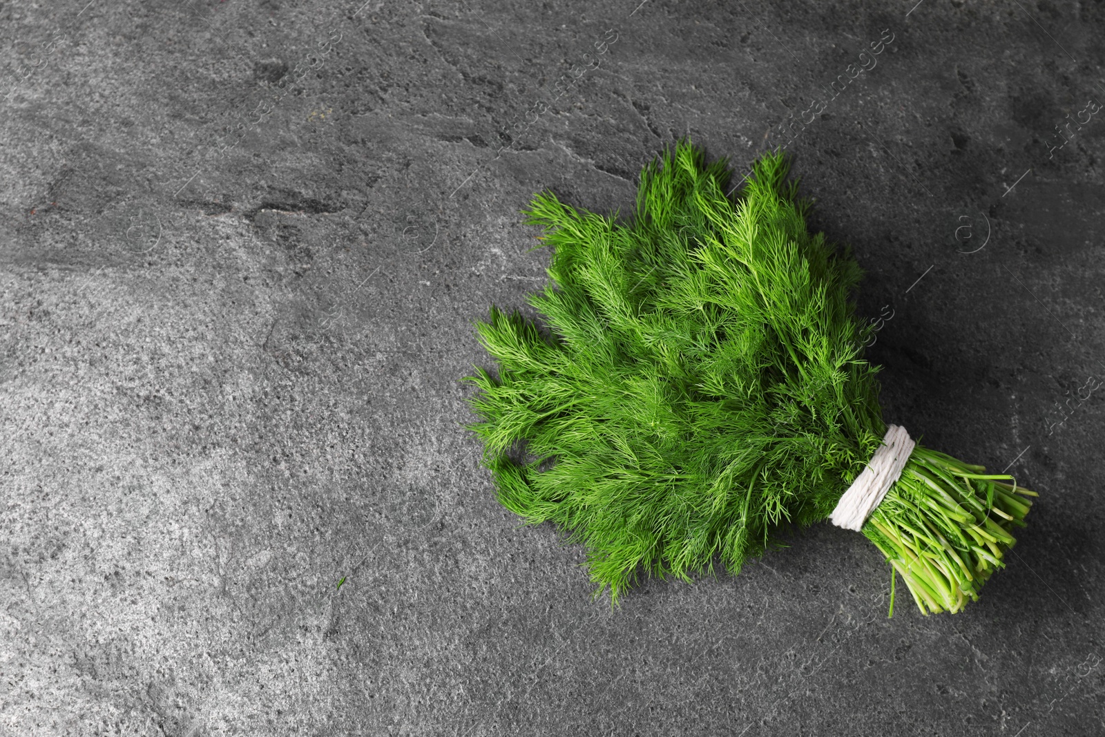 Photo of Bunch of fresh green dill on grey table, top view. Space for text