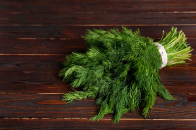 Bunch of fresh green dill on wooden table, space for text