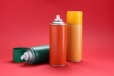 Many spray paint cans on red background