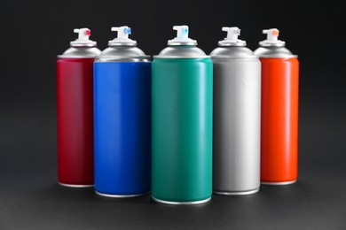 Photo of Many spray paint cans on dark gray background