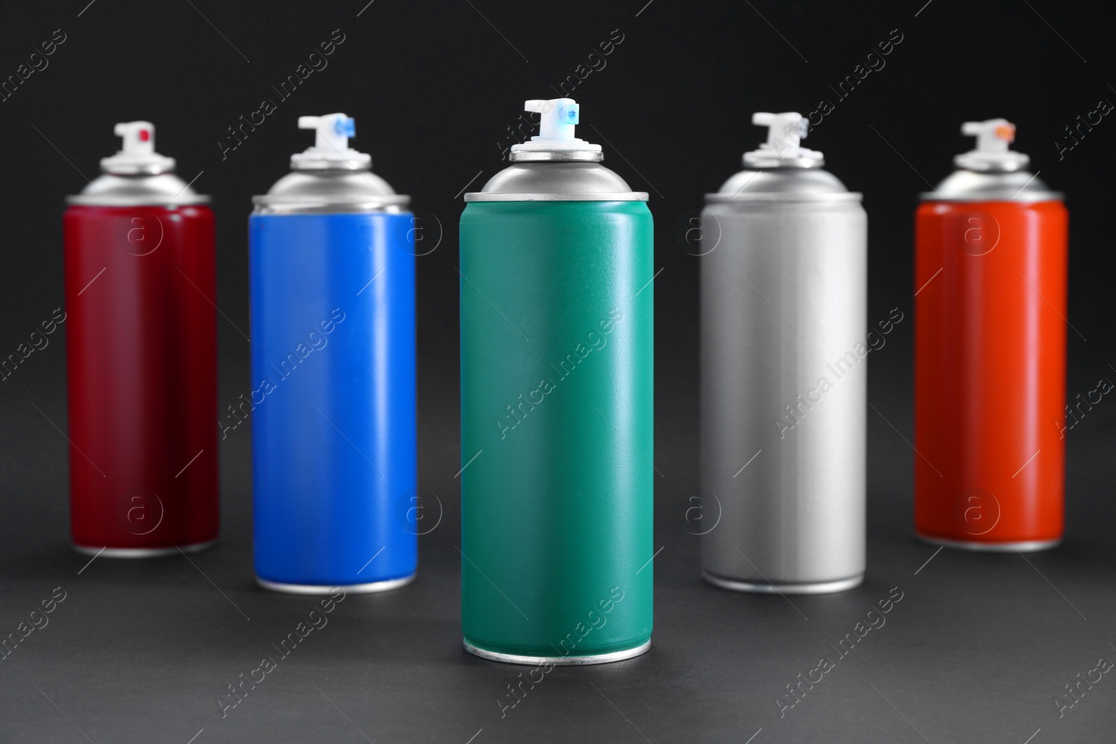 Photo of Many spray paint cans on dark gray background