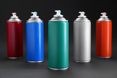 Photo of Many spray paint cans on dark gray background