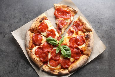 Tasty pepperoni pizza with basil on grey table, top view