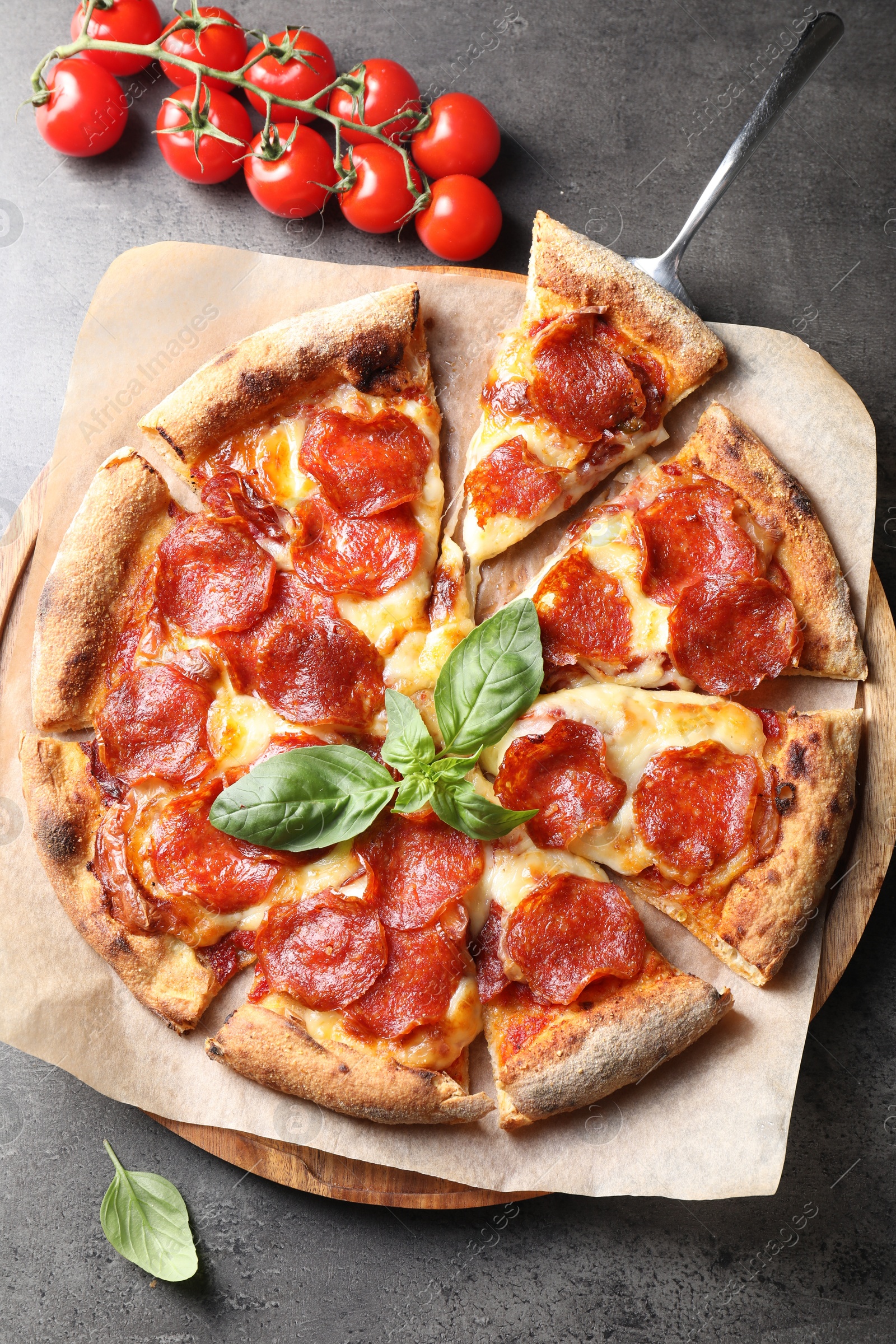 Photo of Tasty pepperoni pizza with basil and tomatoes on grey table, top view