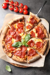 Tasty pepperoni pizza with basil and tomatoes on grey table, top view