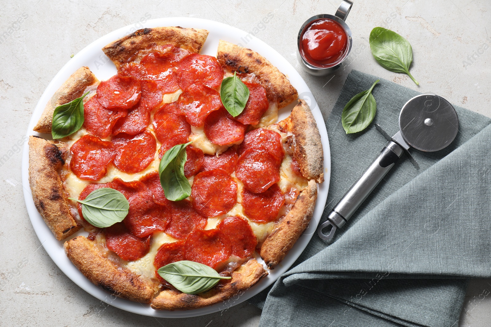 Photo of Tasty pepperoni pizza with basil, sauce and cutter on grey table, top view