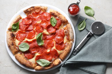 Tasty pepperoni pizza with basil, sauce and cutter on grey table, top view