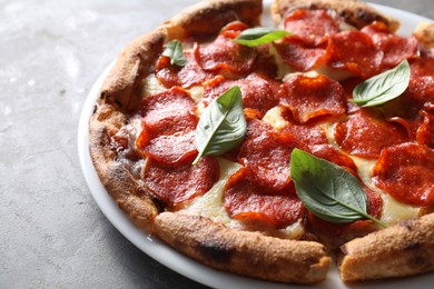 Photo of Tasty pepperoni pizza with basil on grey table, closeup