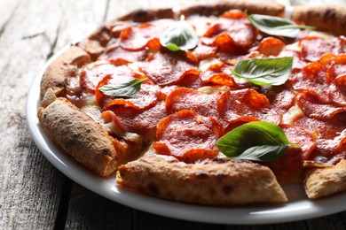 Photo of Tasty pepperoni pizza with basil on wooden table, closeup