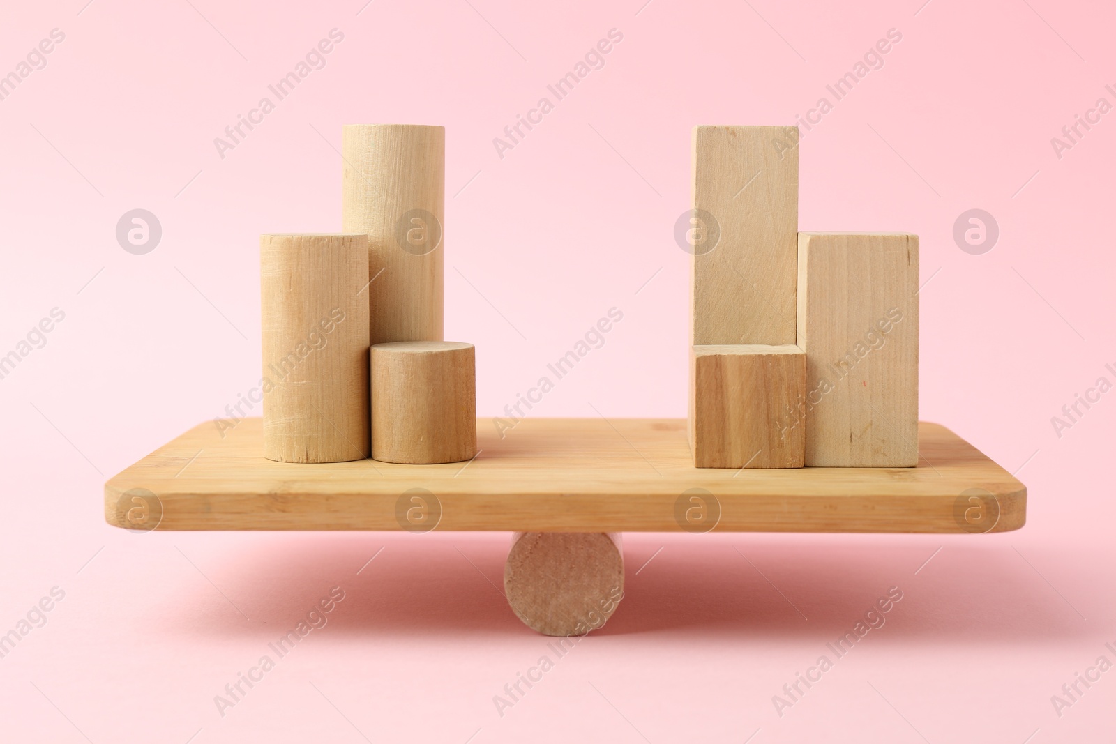 Photo of Equality concept. Balance scale with different wooden blocks on pink background