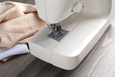 White sewing machine and fabrics on wooden table, closeup