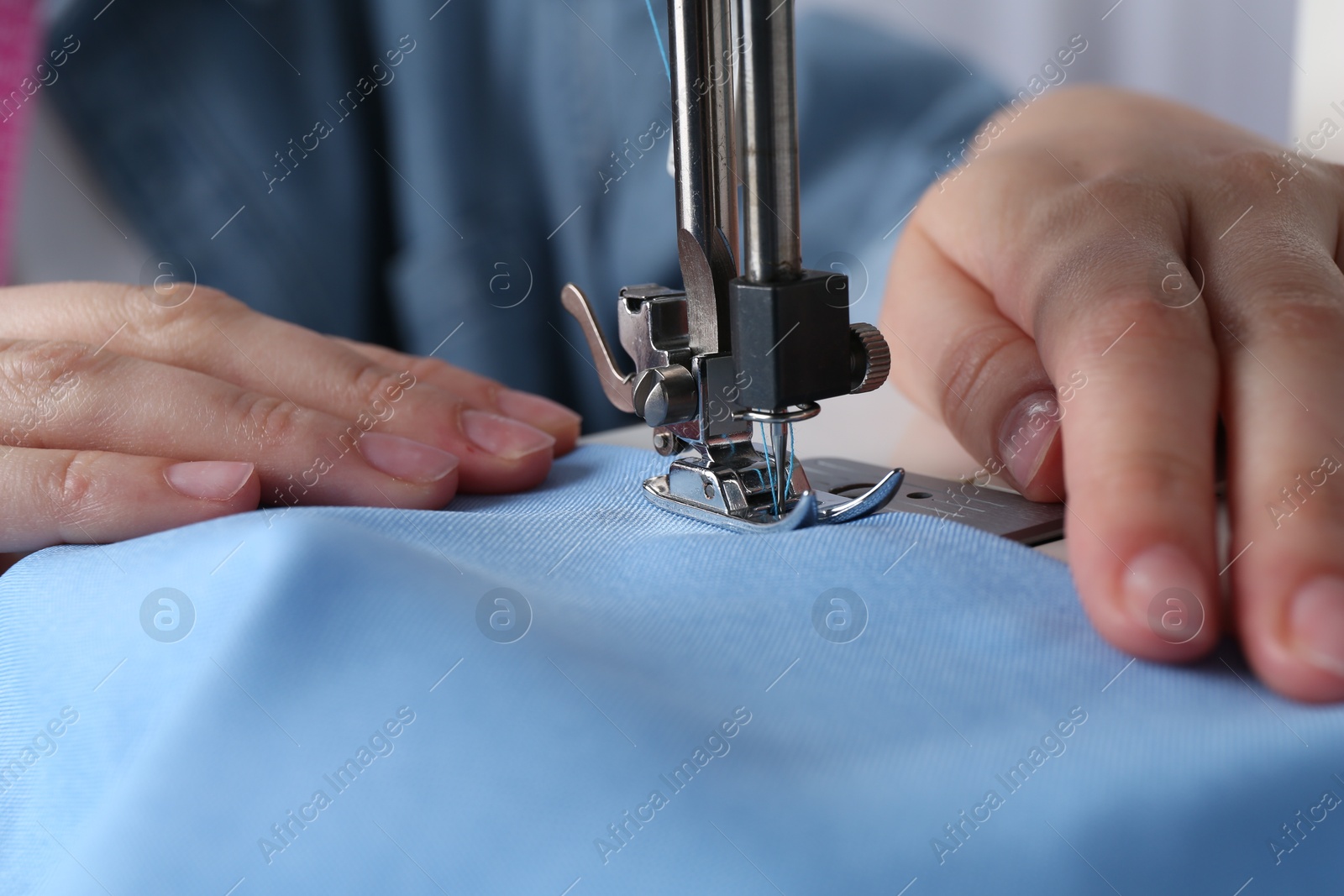 Photo of Seamstress working with sewing machine indoors, closeup