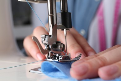 Photo of Seamstress working with sewing machine indoors, closeup