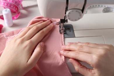 Photo of Seamstress working with sewing machine indoors, closeup