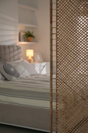 Photo of Folding screen and comfortable bed in bedroom, closeup. Space for text