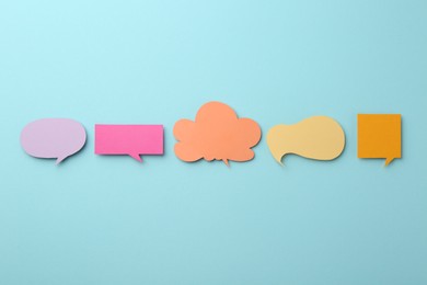 Photo of Equality concept. Different paper speech bubbles on light blue background, flat lay