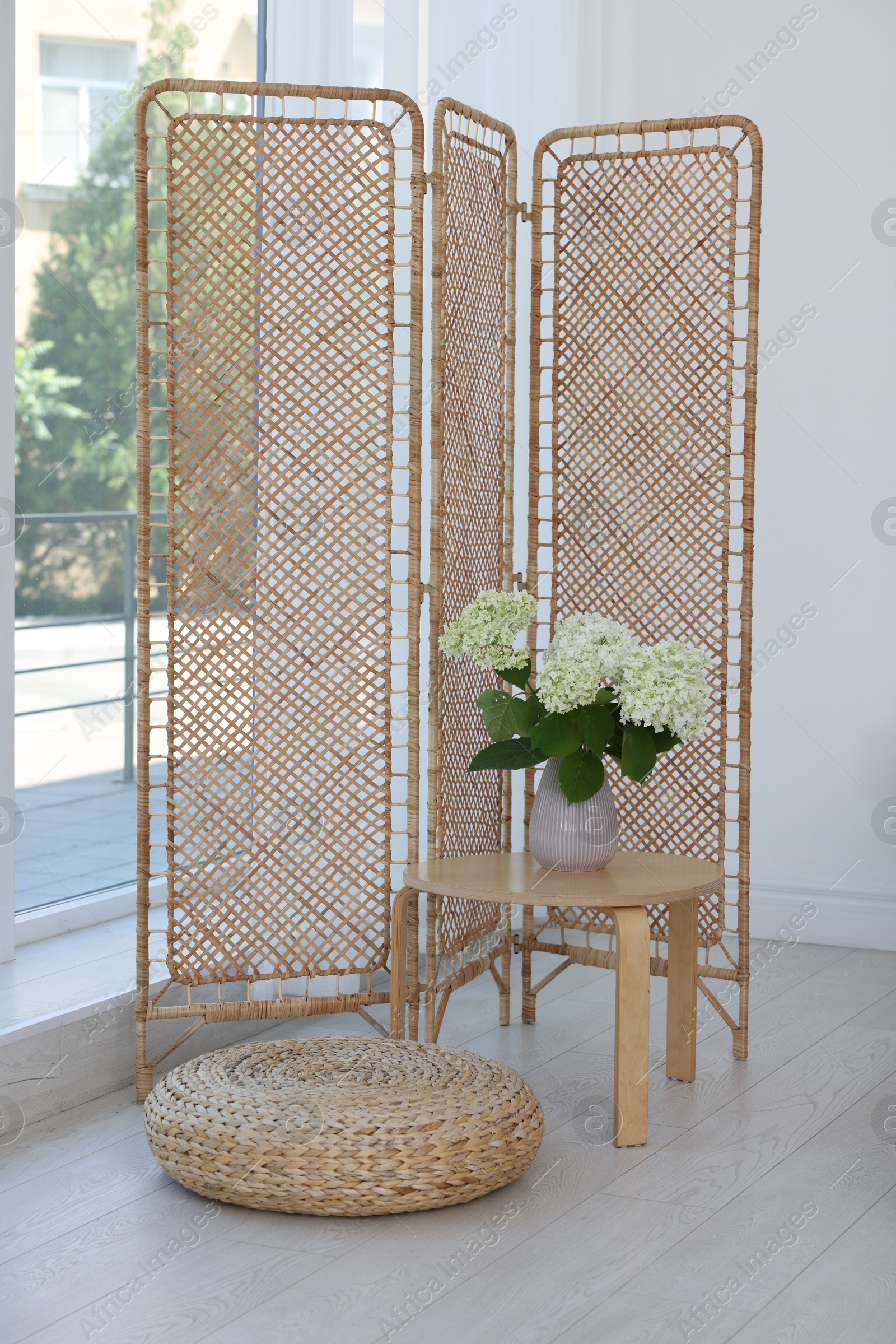 Photo of Folding screen, side table, flowers and pouffe in room