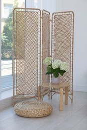 Photo of Folding screen, side table, flowers and pouffe in room