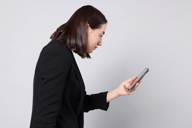 Woman with poor posture using smartphone on gray background