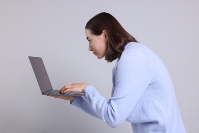 Photo of Woman with poor posture using laptop on gray background