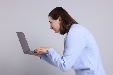 Woman with poor posture using laptop on gray background