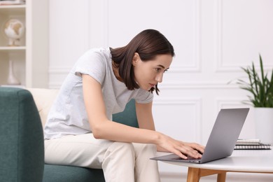 Woman with poor posture using laptop at home