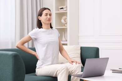 Photo of Woman suffering from back pain at home. Symptom of poor posture