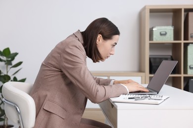 Woman with poor posture working in office