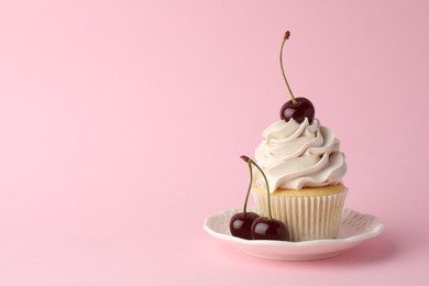 Delicious cupcake with cream and cherries on pink background, space for text