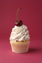 Photo of Delicious cupcake with cream and cherry on red background