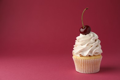 Delicious cupcake with cream and cherry on red background, space for text