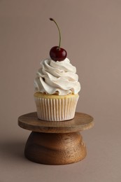 Photo of Delicious cupcake with cream and cherry on dark beige background