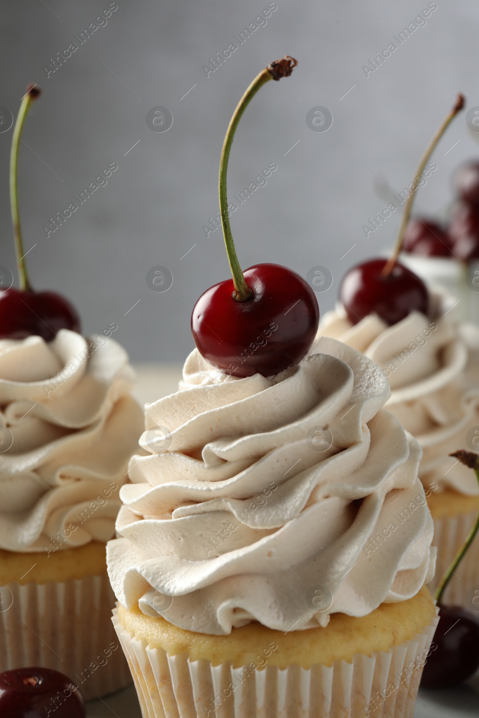 Photo of Delicious cupcakes with cream and cherries on table, closeup