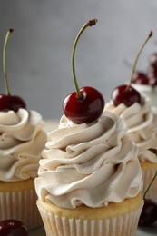 Photo of Delicious cupcakes with cream and cherries on table, closeup