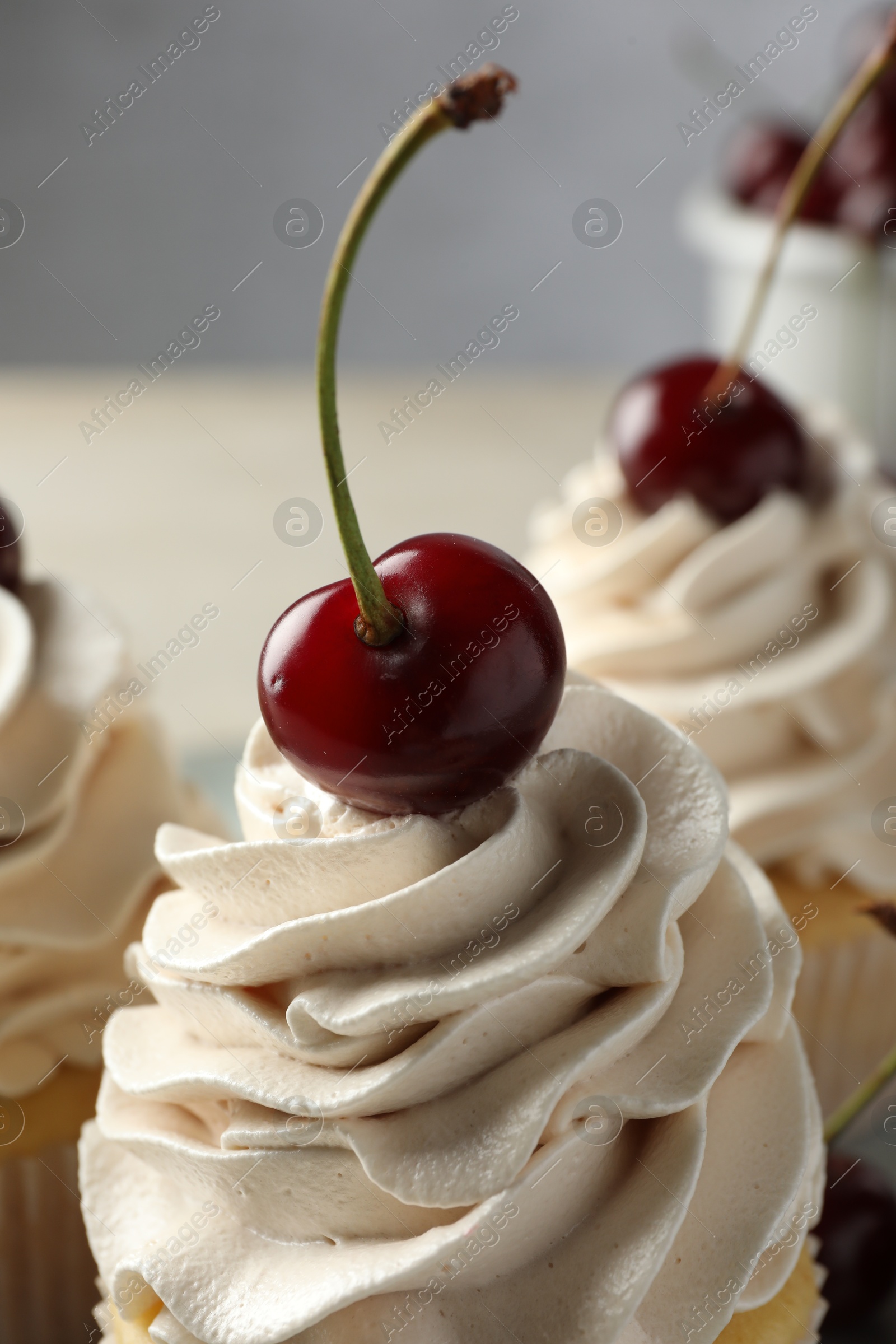 Photo of Delicious cupcakes with cream and cherries on table, closeup