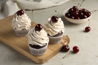 Photo of Delicious cupcakes with cream and cherries on light textured table