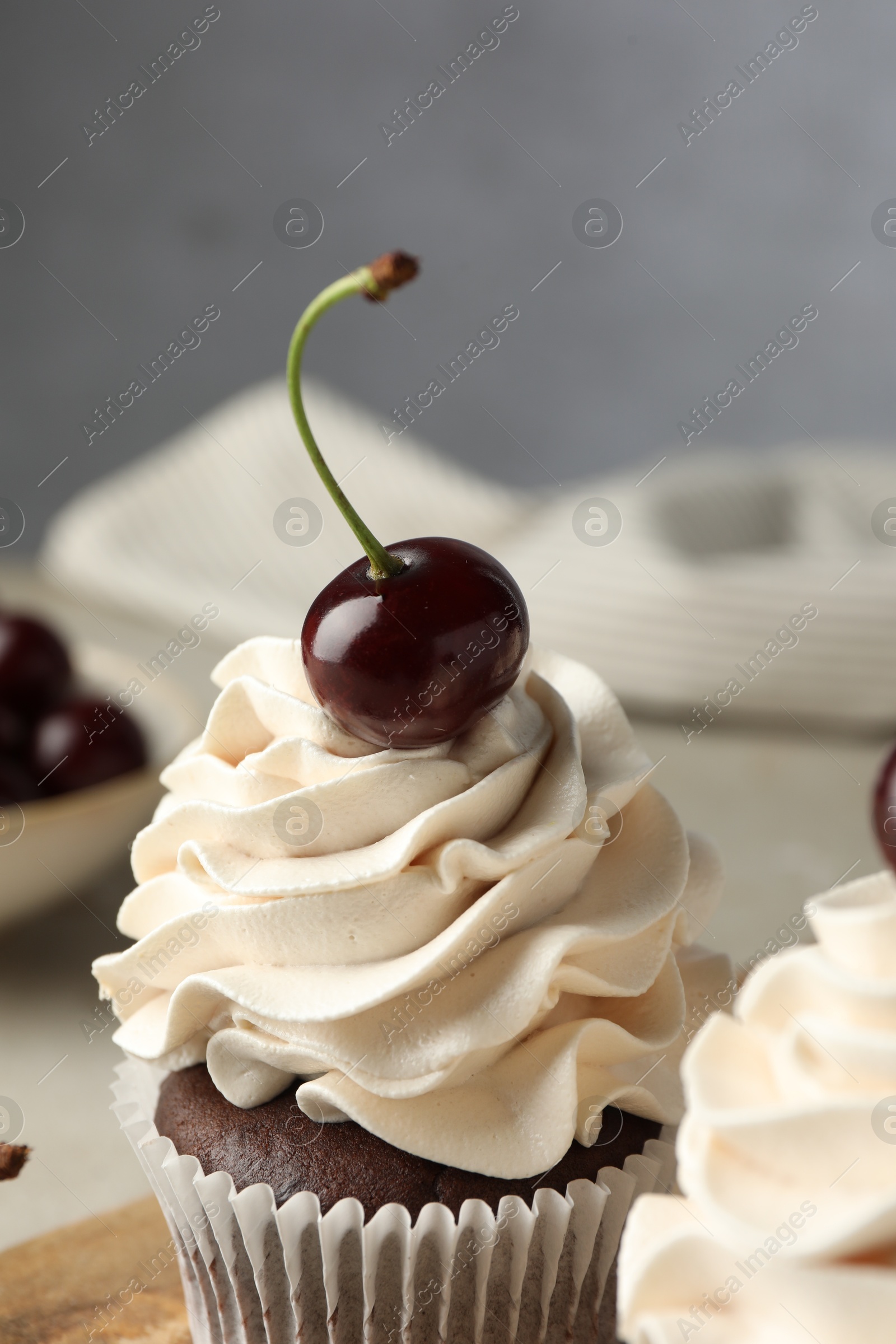 Photo of Delicious cupcakes with cream and cherry on table, closeup