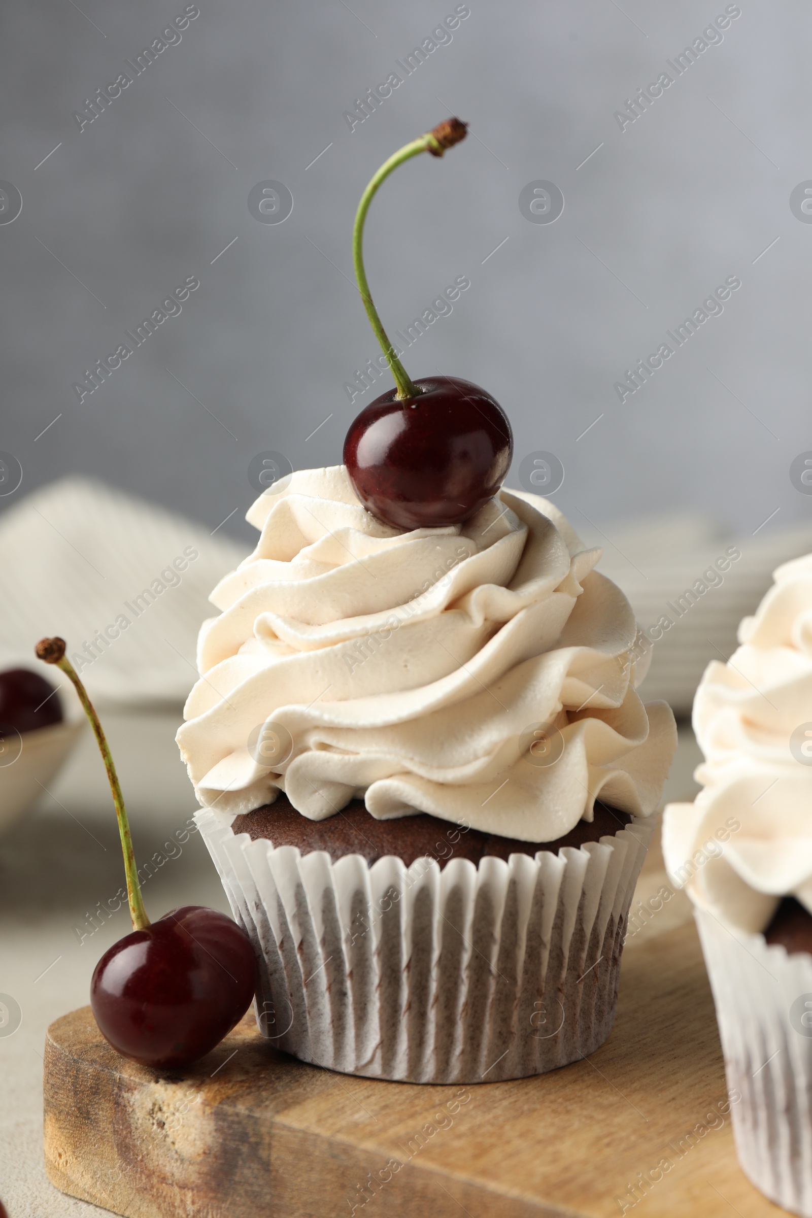 Photo of Delicious cupcakes with cream and cherries on table, closeup