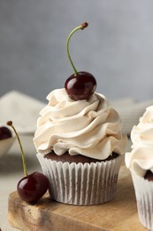 Photo of Delicious cupcakes with cream and cherries on table, closeup