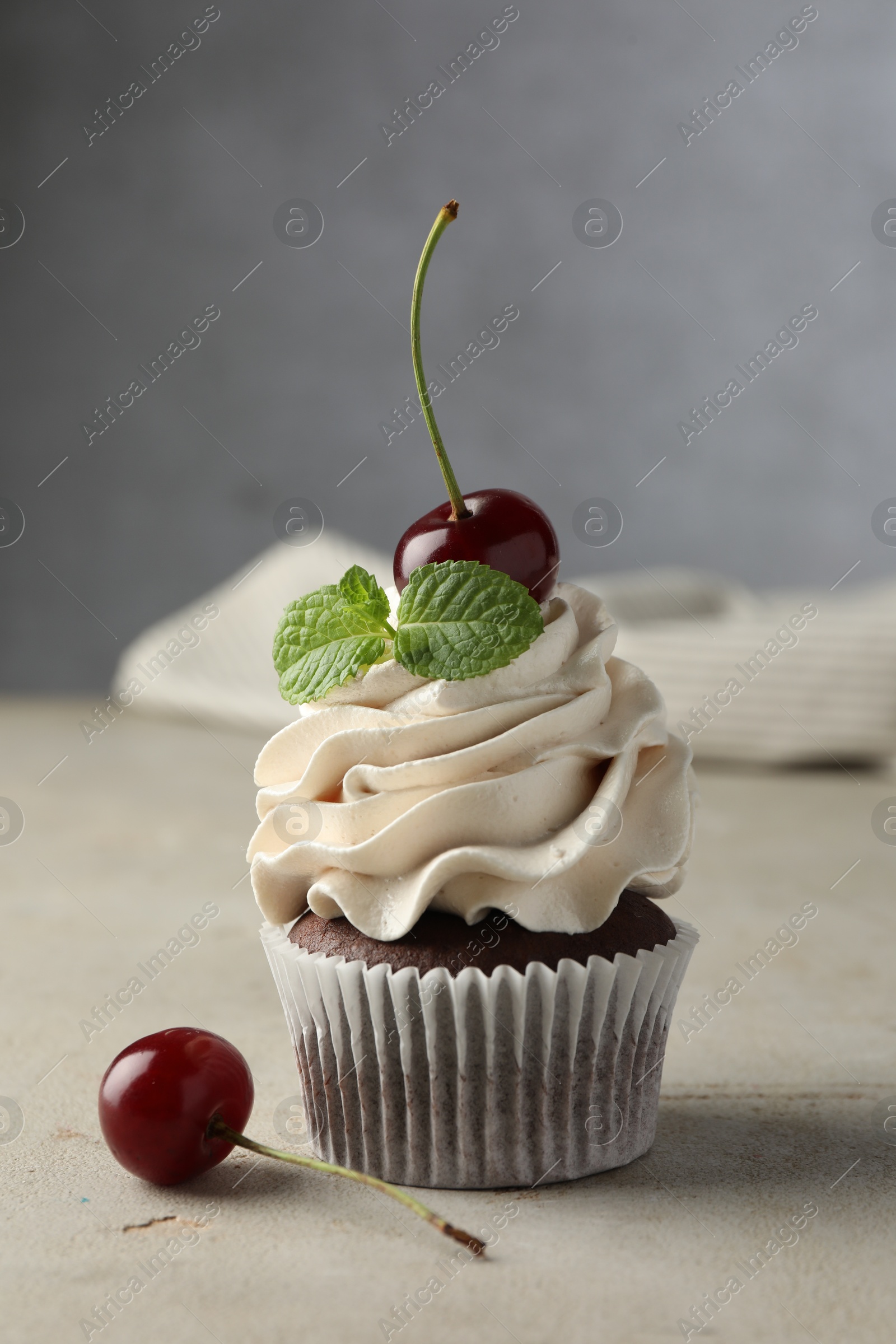 Photo of Delicious cupcake with cherries and fresh mint on light textured table, closeup