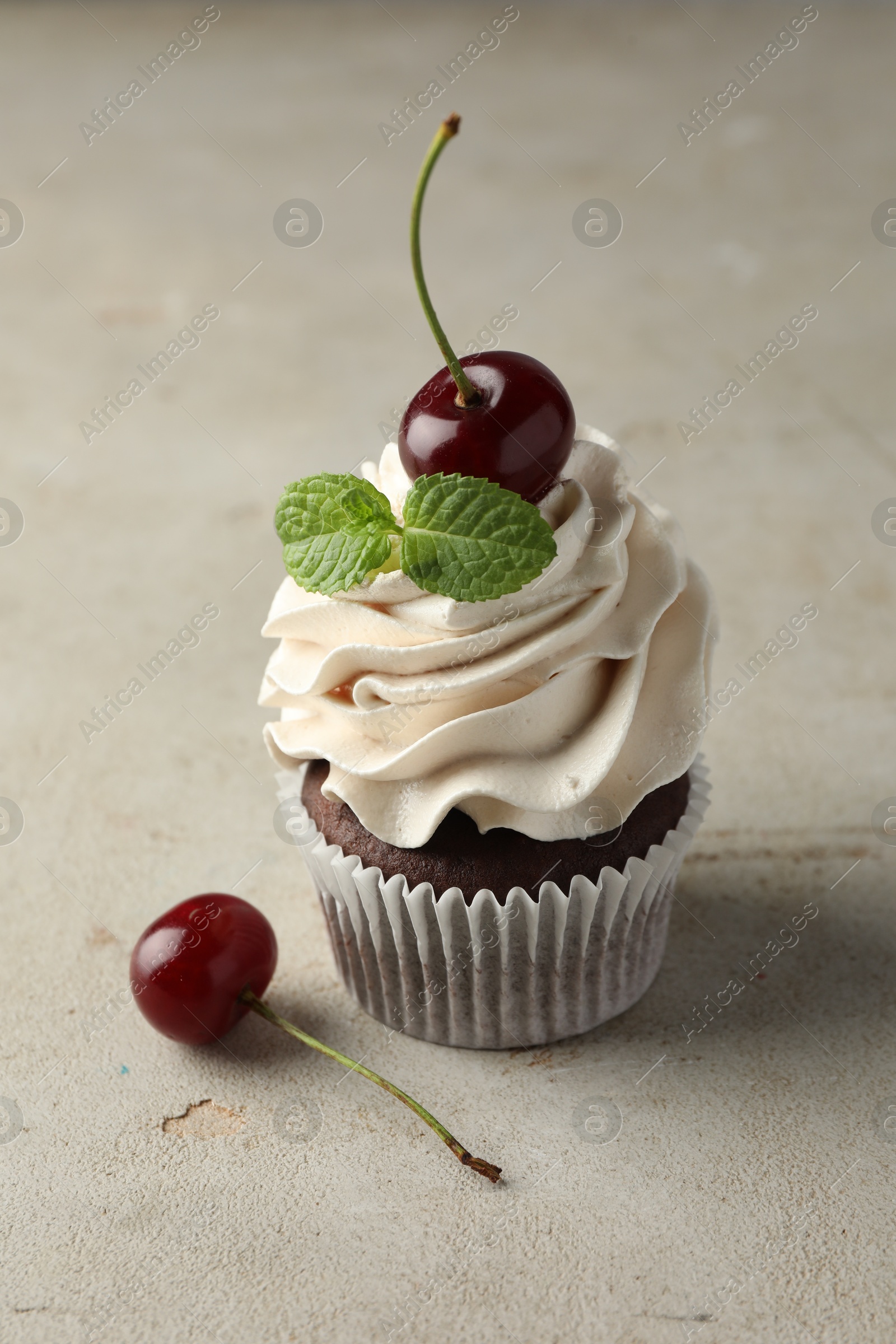 Photo of Delicious cupcake with cherries and fresh mint on light textured table