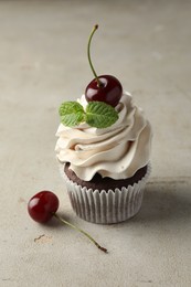 Delicious cupcake with cherries and fresh mint on light textured table