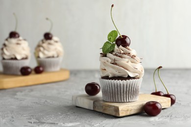 Delicious cupcake with cream and cherries on grey textured table