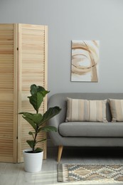 Photo of Wooden folding screen, sofa and houseplant in living room