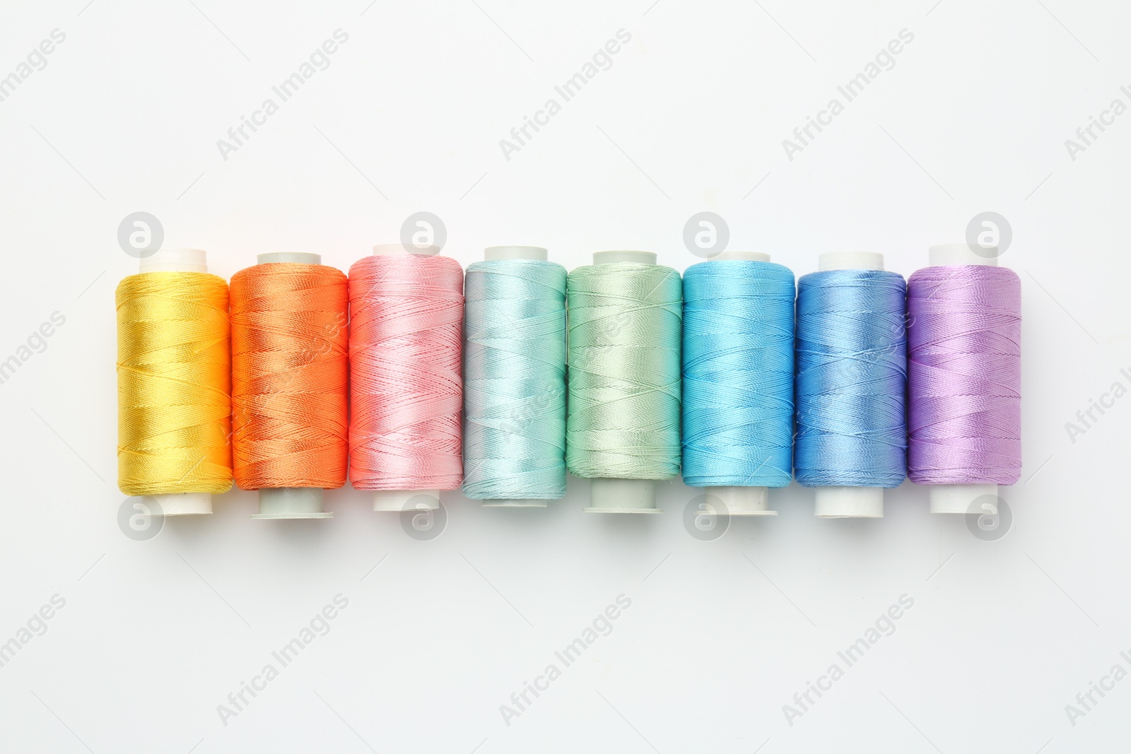 Photo of Spools of sewing threads on white background, flat lay