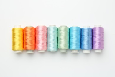 Photo of Spools of sewing threads on white background, flat lay